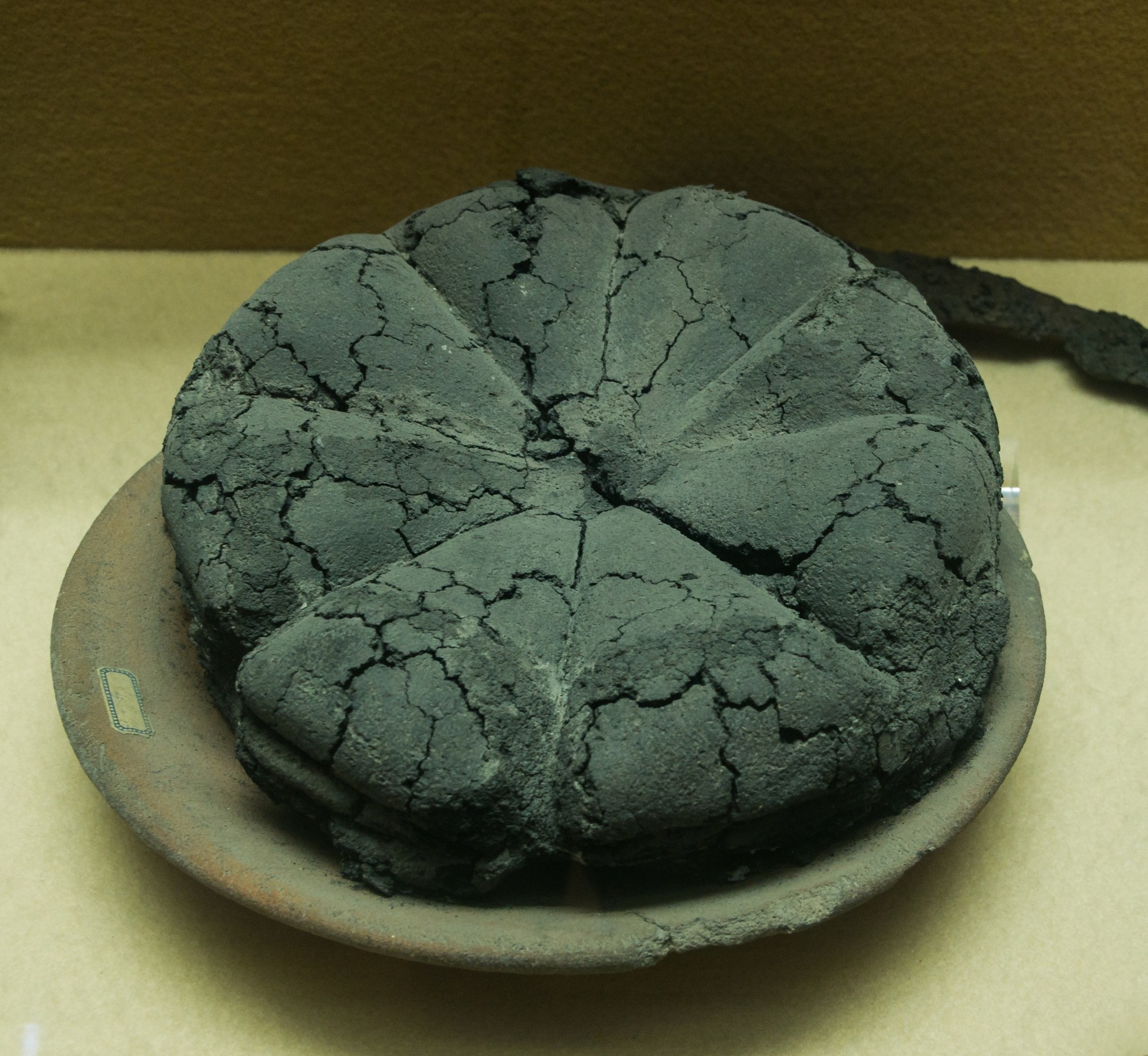 Blackened round loaf divided into wedge-shaped sections.