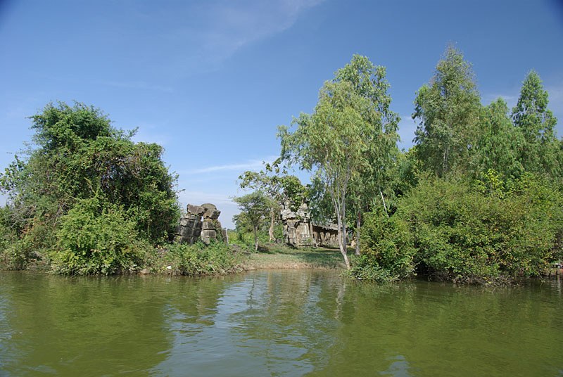 Trees and stone remains of the West Mebon temple seen from the water.