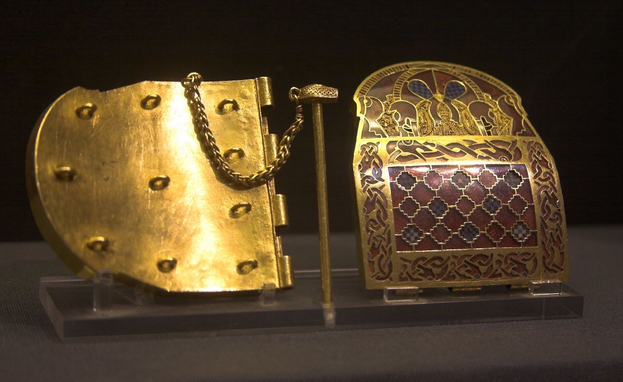 An opened Sutton Hoo shoulder clasp showing a plain gold reverse beside a garnet-and-glass decorated face.