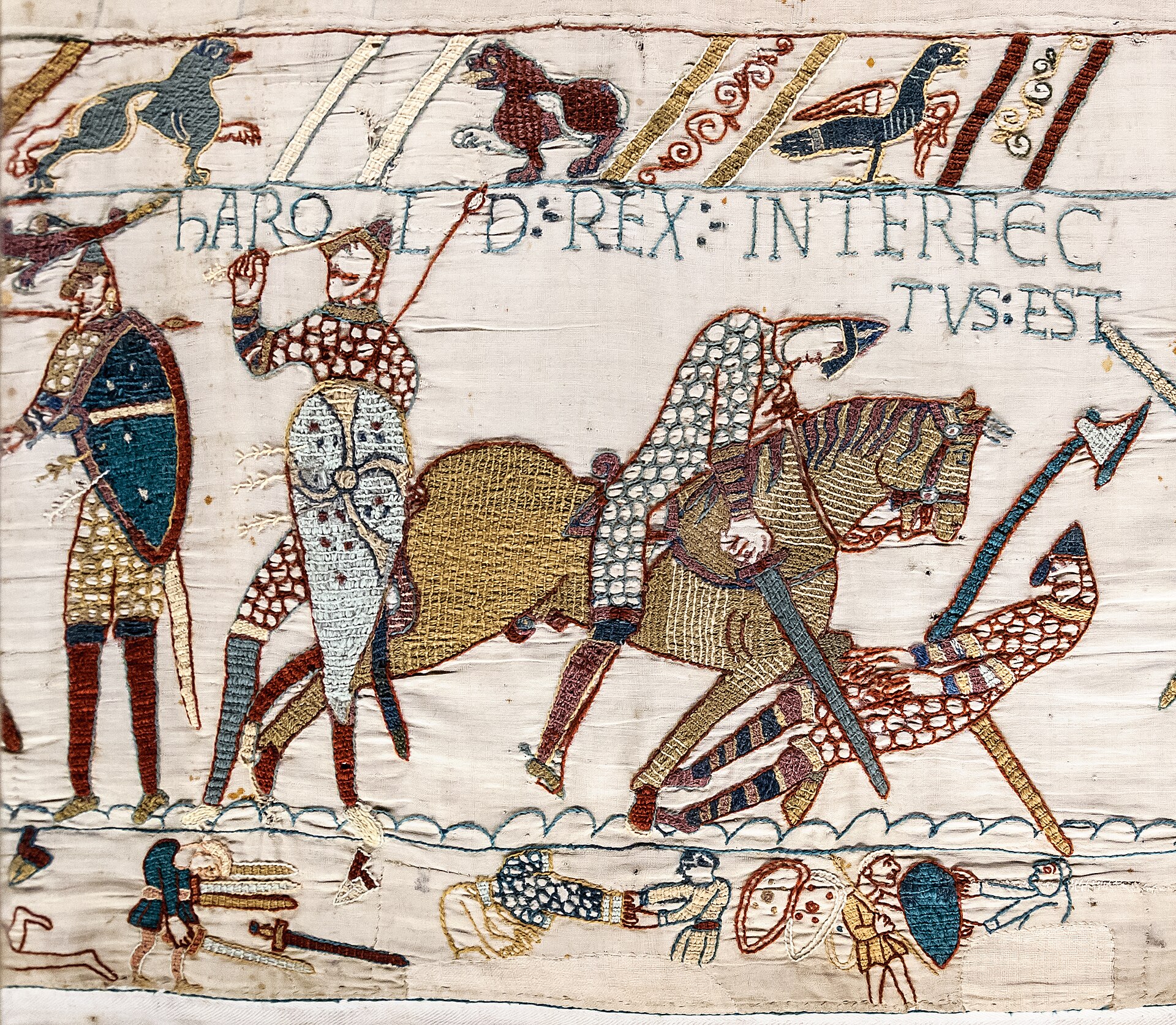 Warriors beneath the inscription announcing Harold’s death, with bodies and discarded equipment in the lower border.