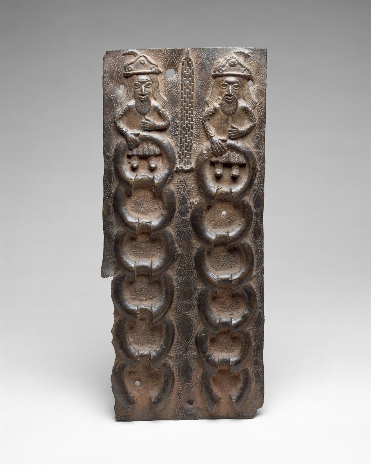 Narrow brass plaque with Portuguese figures and bracelet-shaped metal manillas