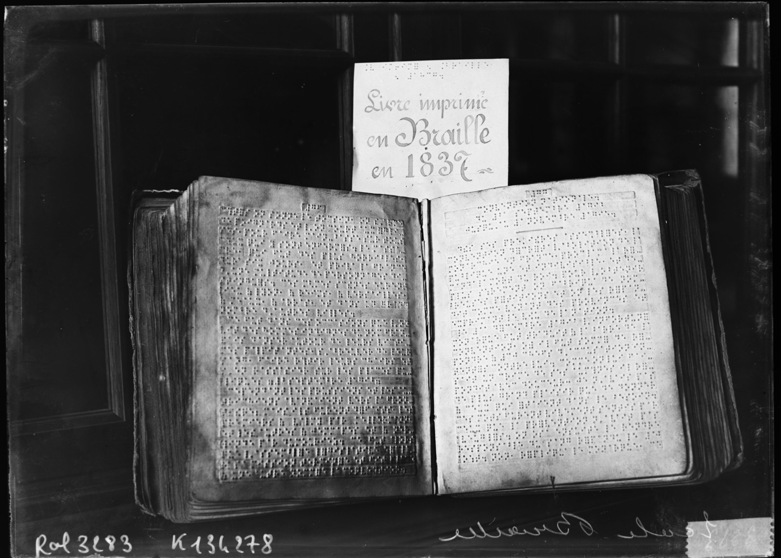 Open historical book with embossed braille text photographed in black and white