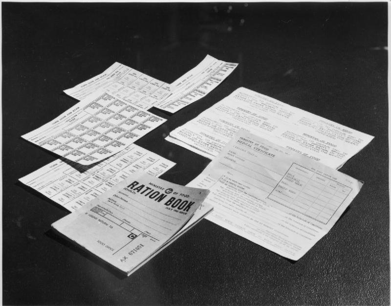 A child’s ration book issued in July 1943 beside food coupons, priority vouchers and a medical certificate.
