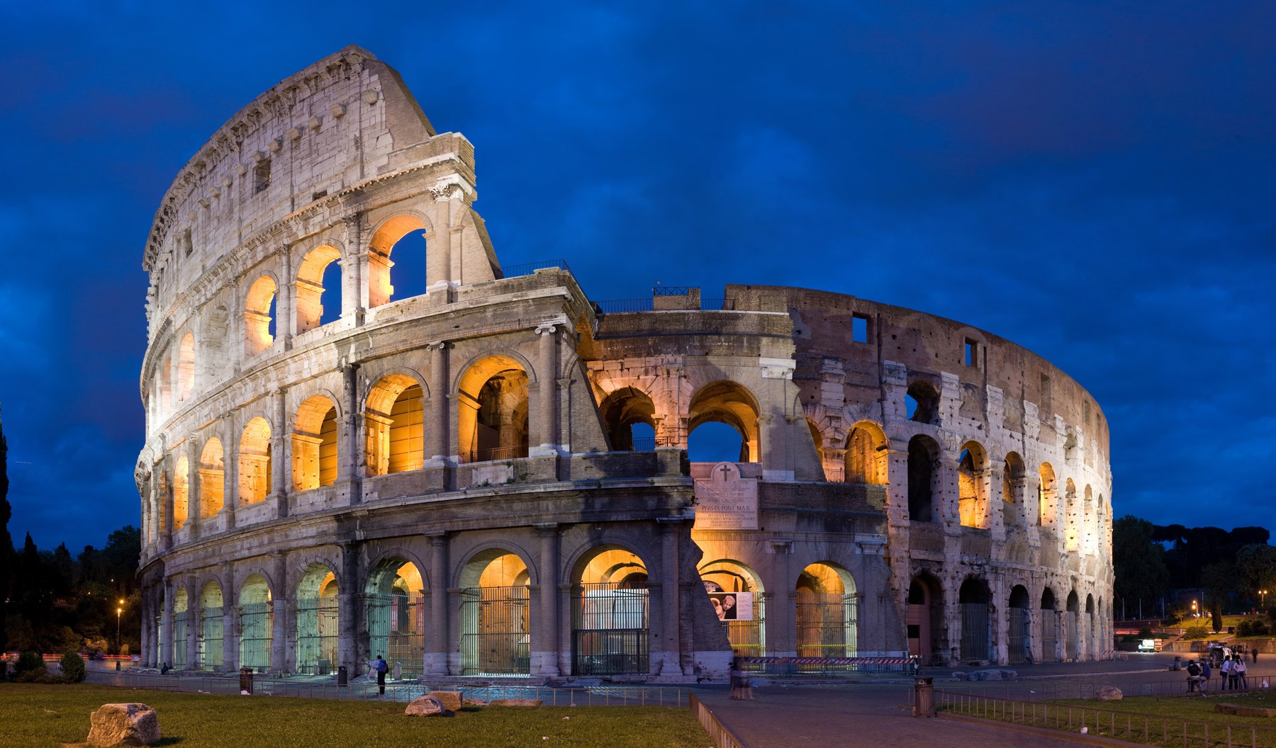 The Colosseum's surviving outer arcades illuminated at dusk in Rome