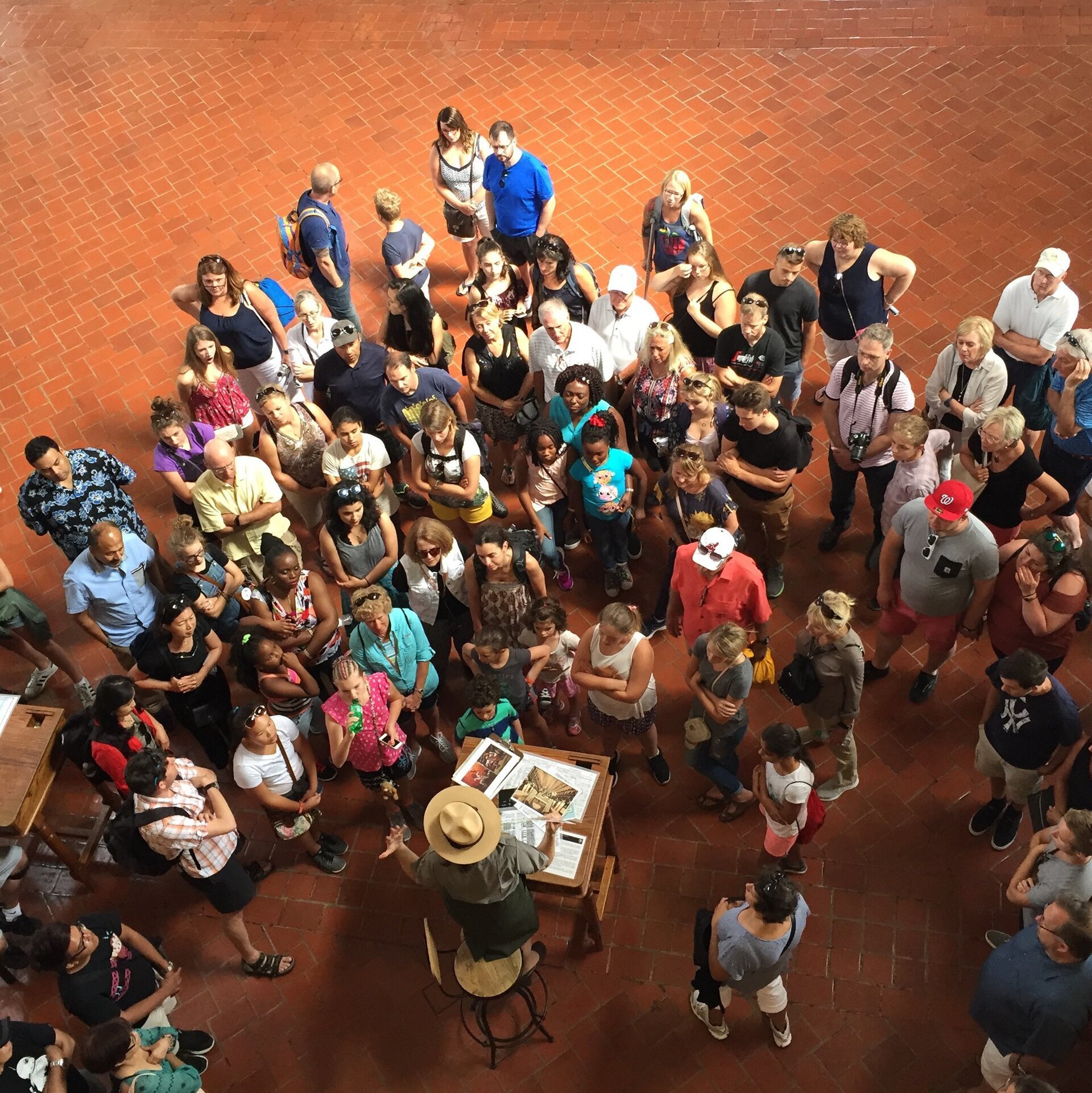 A group of museum visitors gathered around a park ranger, photographed from above.