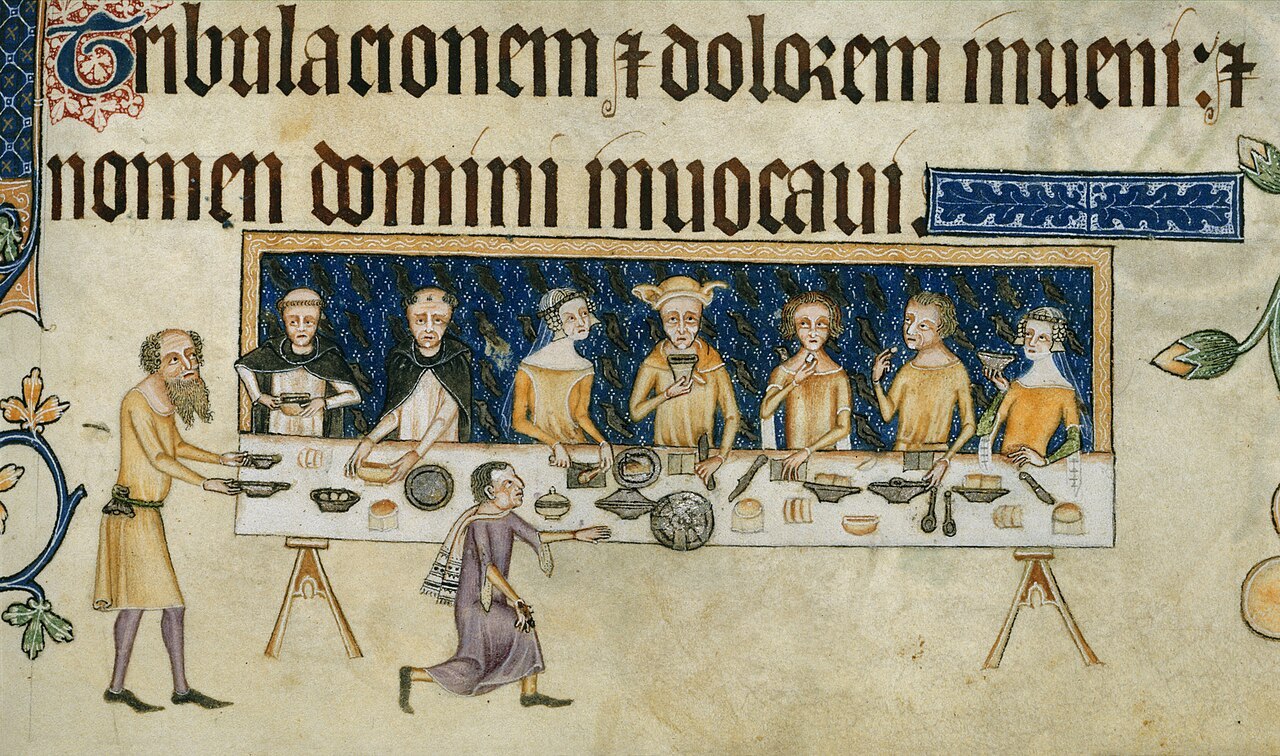 Medieval diners seated at a long table while servants bring food and drink