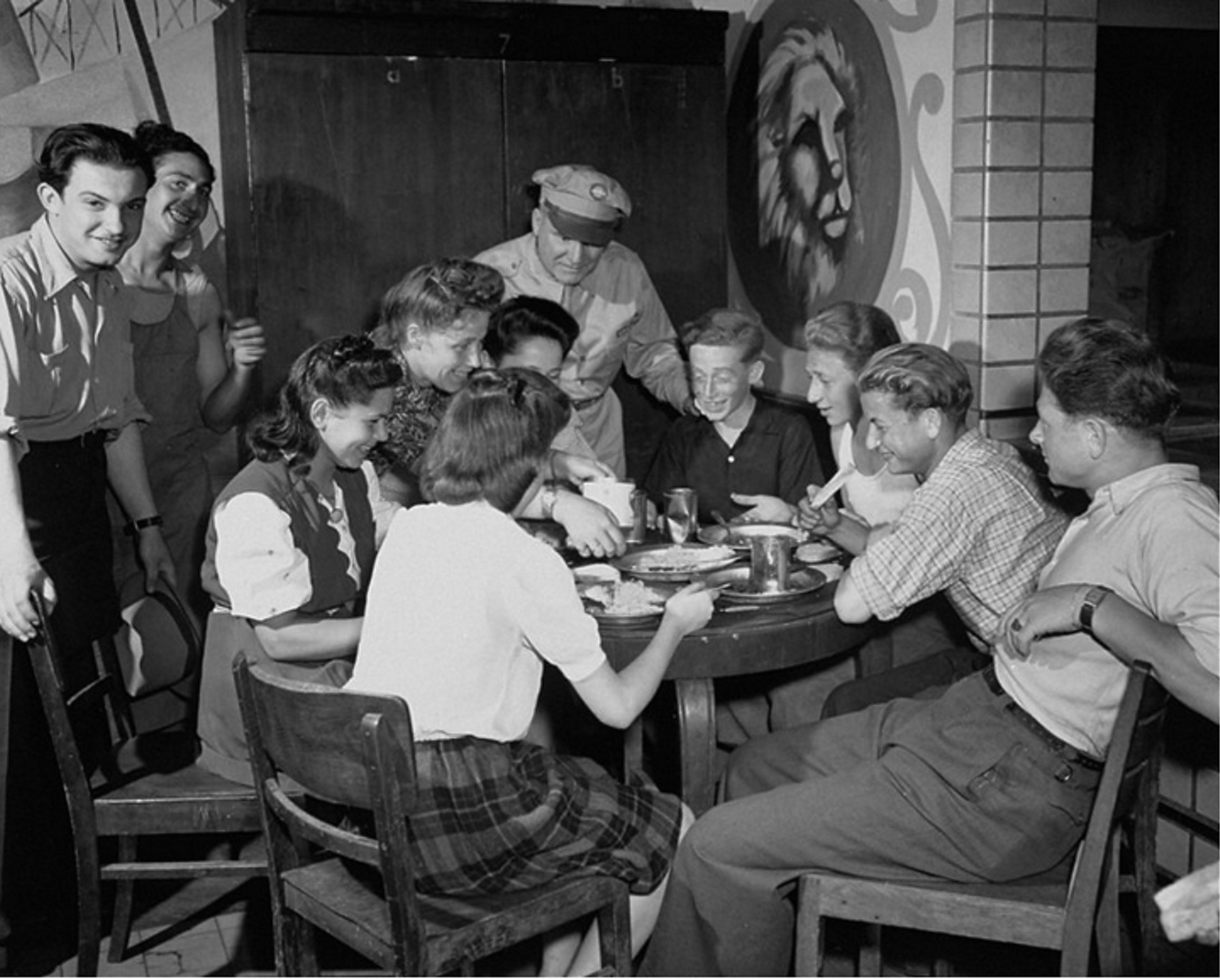 An UNRRA officer stands beside young refugees gathered around a table at Eschwege displaced persons camp in July 1946.
