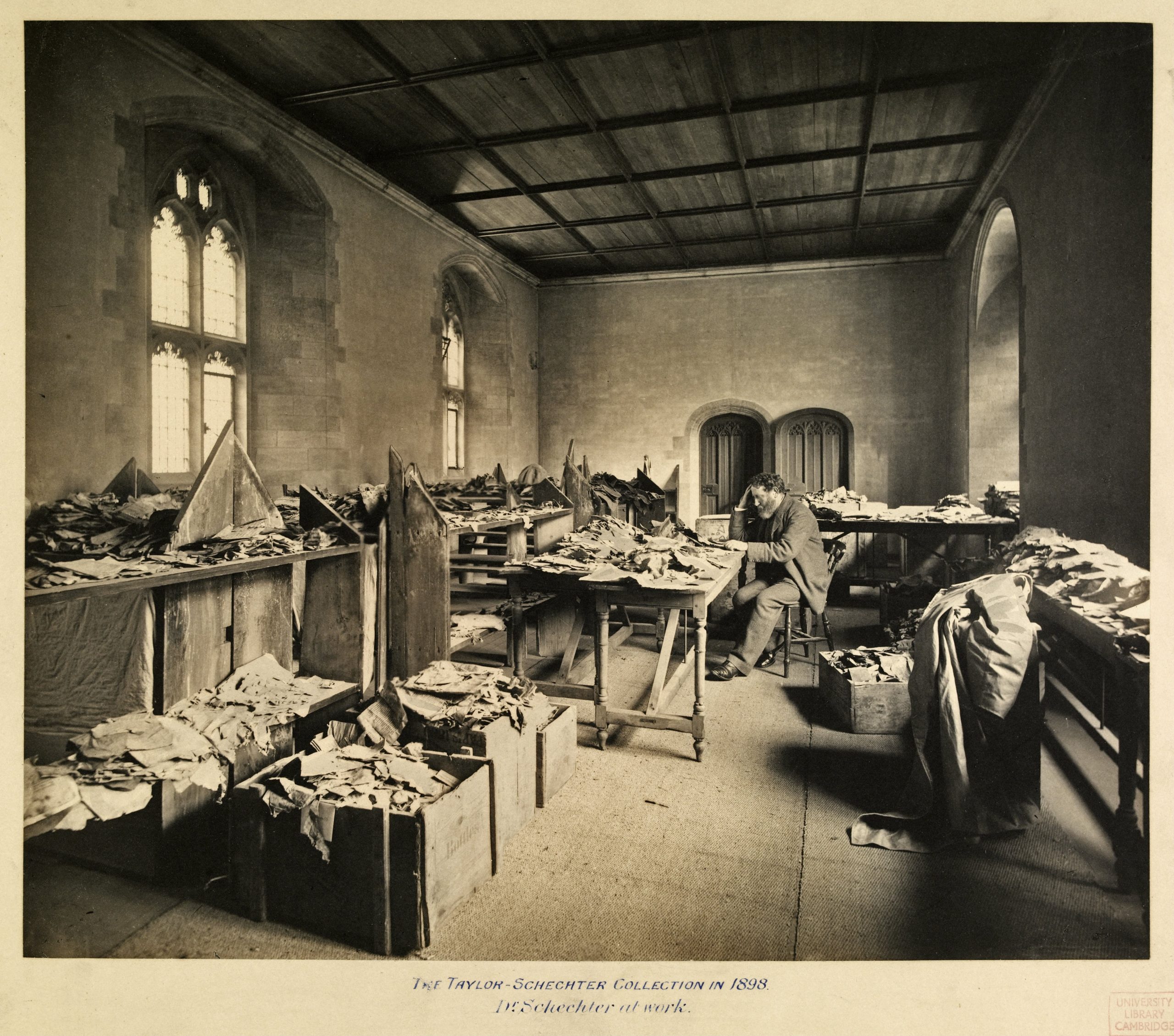 Solomon Schechter sits at a table covered with manuscript fragments from the Cairo Geniza, about 1898.