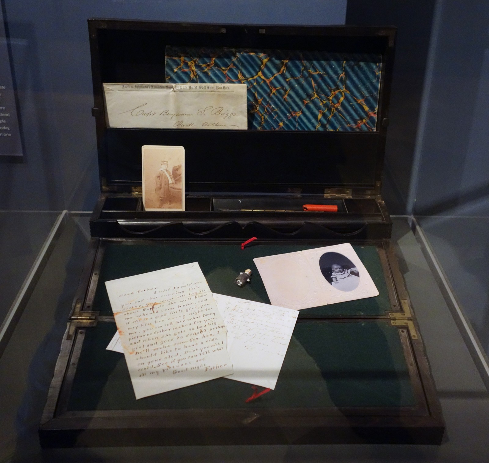 Open wooden lap desk associated with Captain Briggs, displayed with papers and small personal items at the Peabody Essex Museum
