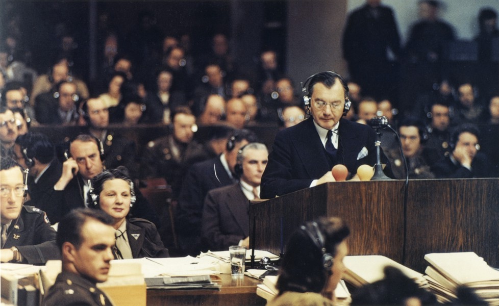 U.S. chief prosecutor Robert H. Jackson addresses the Nuremberg tribunal while lawyers and observers listen through headphones.