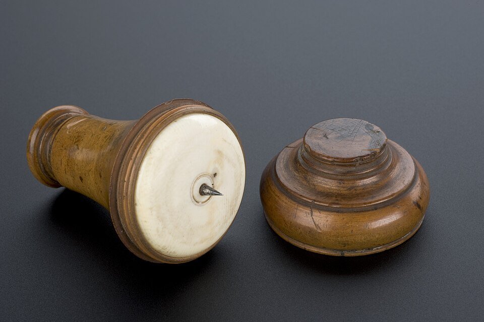 An ivory and boxwood medical instrument displayed on a dark background