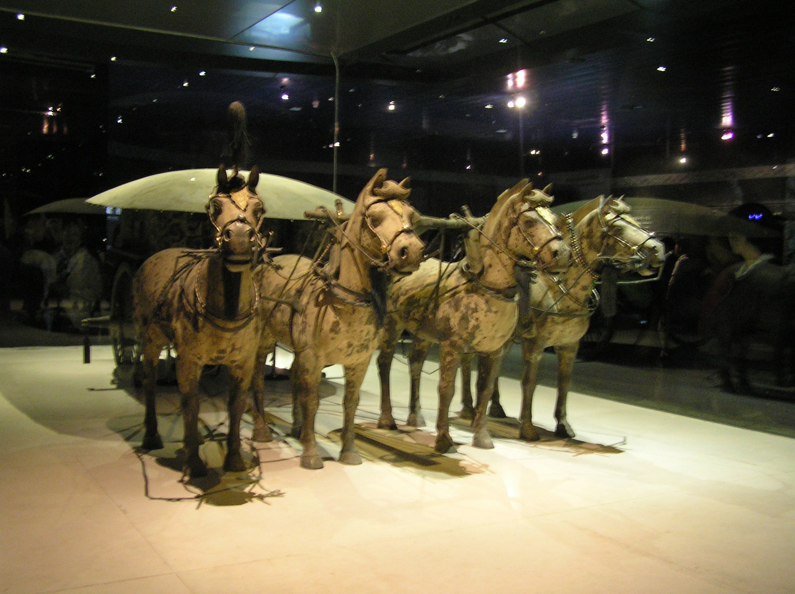 Four bronze horses harnessed to a small chariot in a display case
