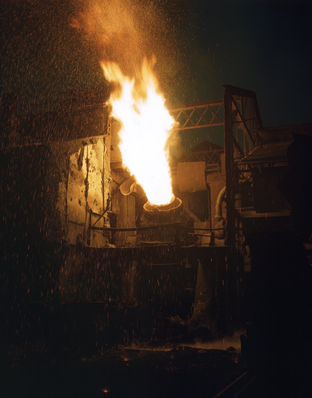 A glowing Bessemer converter pours a stream of molten metal at a 1941 steelworks.