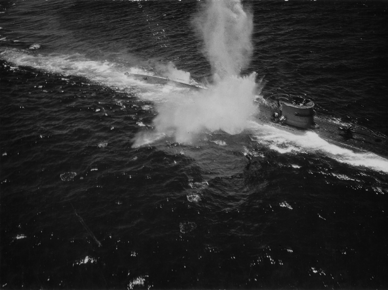 An aircraft’s attack sends spray over German submarine U-118 on the Atlantic surface on 12 June 1943.