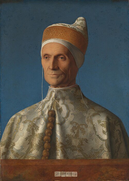 Portrait of Leonardo Loredan wearing a cream and gold patterned ducal robe and pointed cap against a blue background.