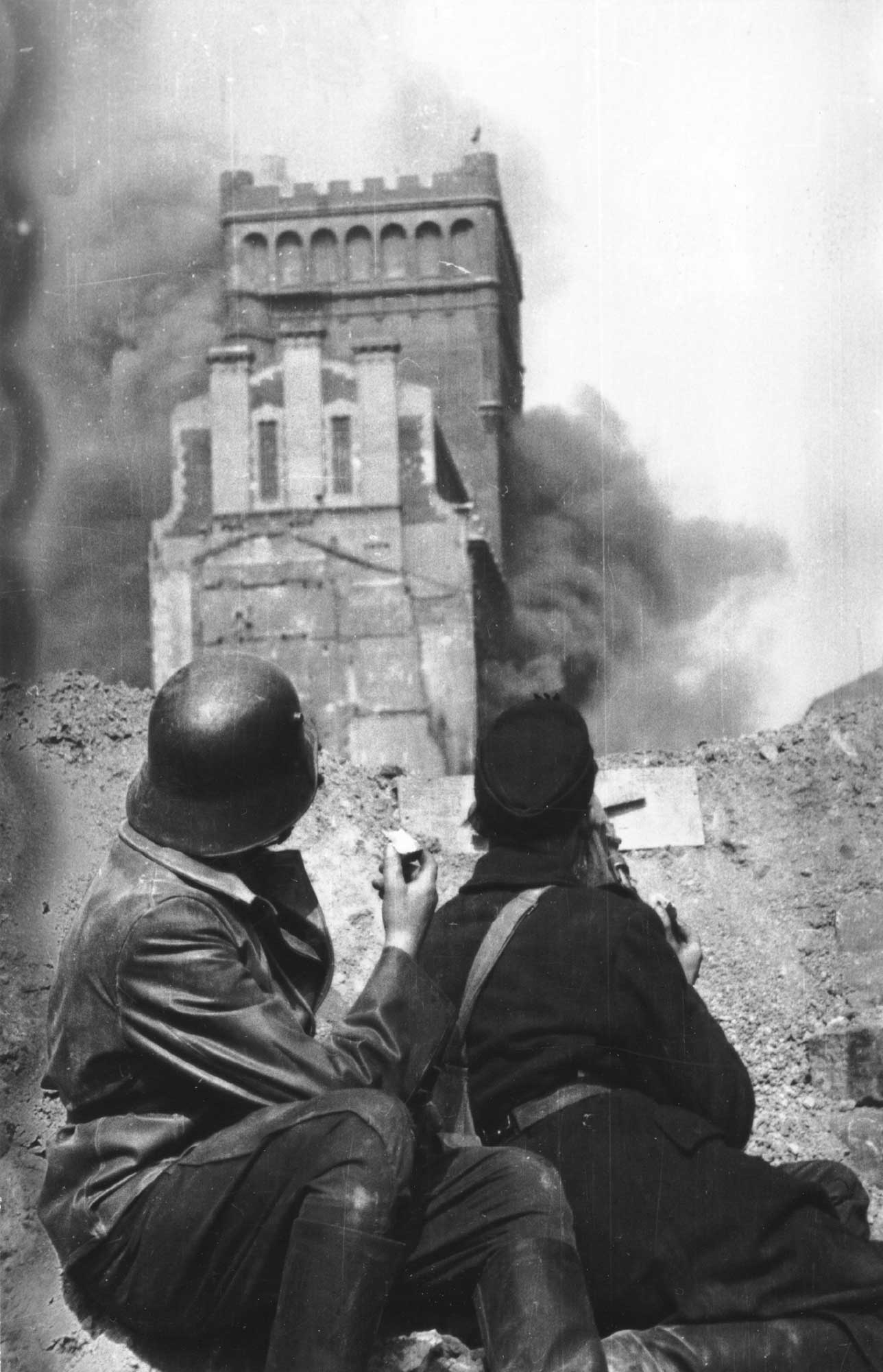 Polish insurgents behind a Zielna Street barricade watch smoke from the burning PASTa building on 20 August 1944.